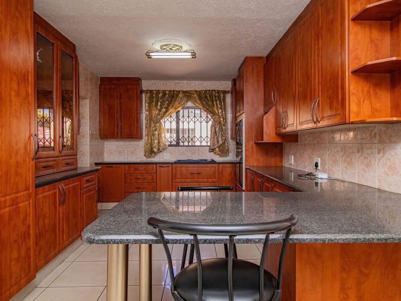 A functional kitchen featuring extensive wooden cabinetry, granite countertops, tiled flooring, and a built-in oven, offering ample storage and workspace.
