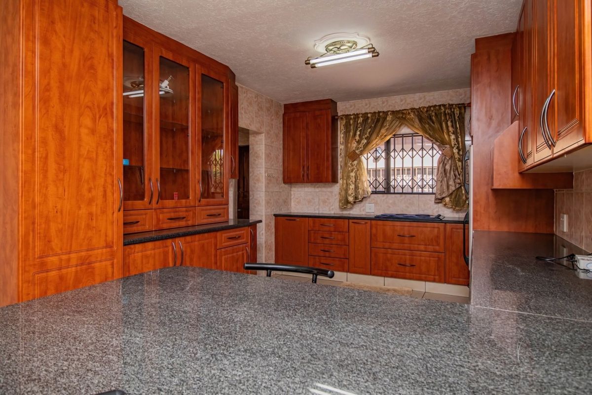 A functional kitchen featuring extensive wooden cabinetry, granite countertops, and tiled backsplash, offering ample storage and workspace.