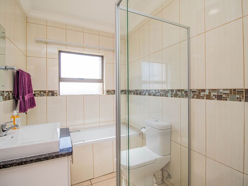 A clean, functional bathroom featuring a built-in vanity with granite countertop, a bathtub, a toilet, and a separate glass-enclosed shower with tiled walls.