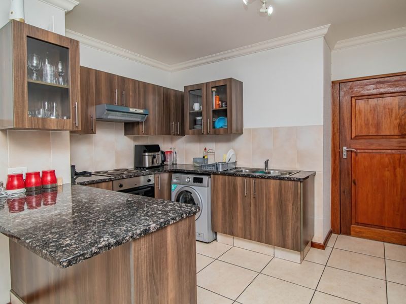 A functional kitchen featuring wood-finish cabinetry, granite countertops, a built-in oven with extractor fan, and tiled flooring.
