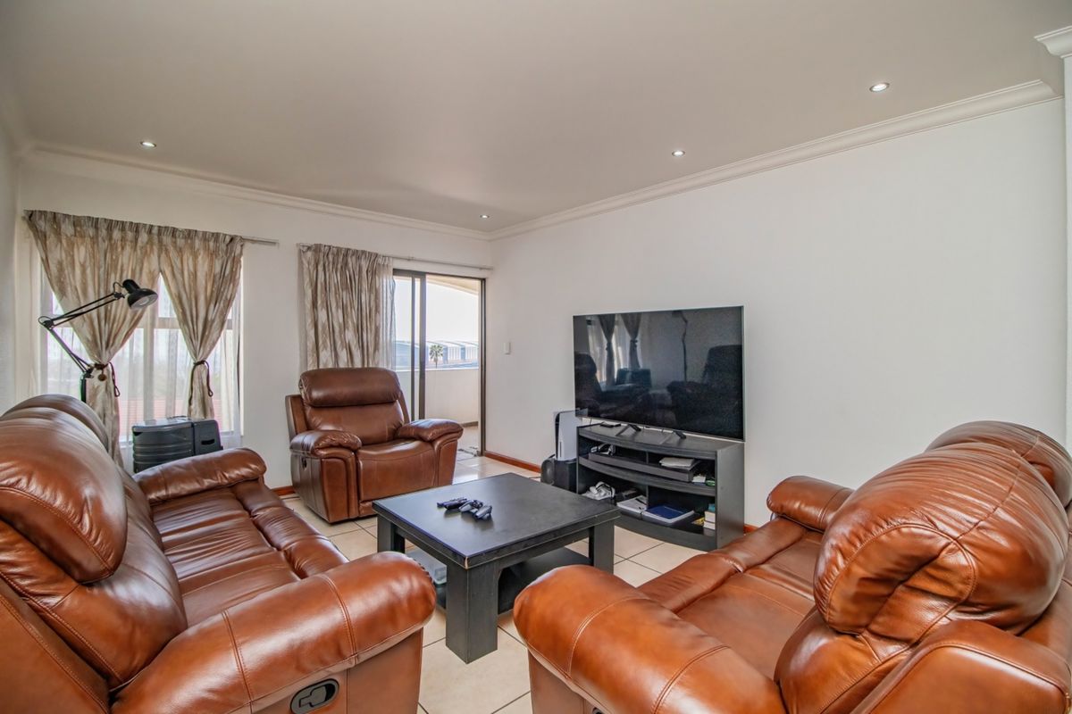 A comfortable living room featuring tiled flooring, recessed downlighting, and a sliding glass door providing access to an outdoor balcony area.