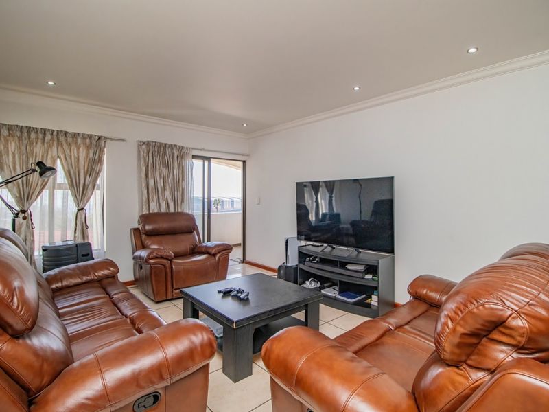 A comfortable living room featuring tiled flooring, recessed downlighting, and a sliding glass door providing access to an outdoor balcony area.