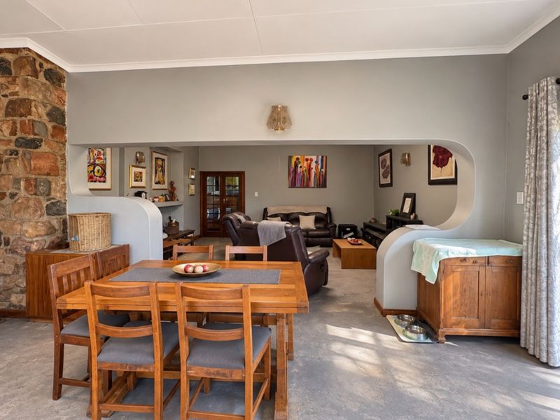 Open plan living and dining area featuring a prominent stone fireplace and a unique curved partition wall separating the spaces.