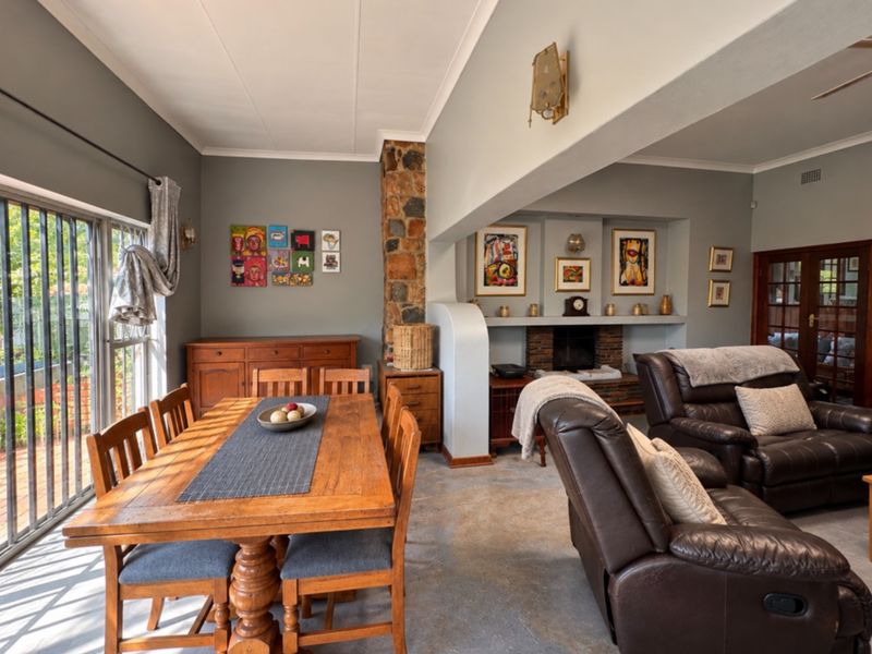 Spacious open-plan living and dining area featuring a stone fireplace, recessed shelving, and large sliding glass doors providing natural light.