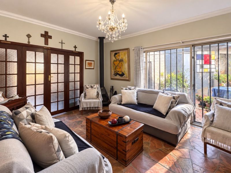 A cozy living room featuring flagstone flooring, a crystal chandelier, a freestanding fireplace, and sliding glass doors leading to an outdoor area.