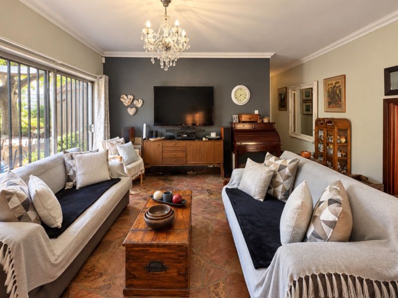 A comfortable living room featuring stone tile flooring, crown molding, and large sliding glass doors that provide access to the outdoor area.