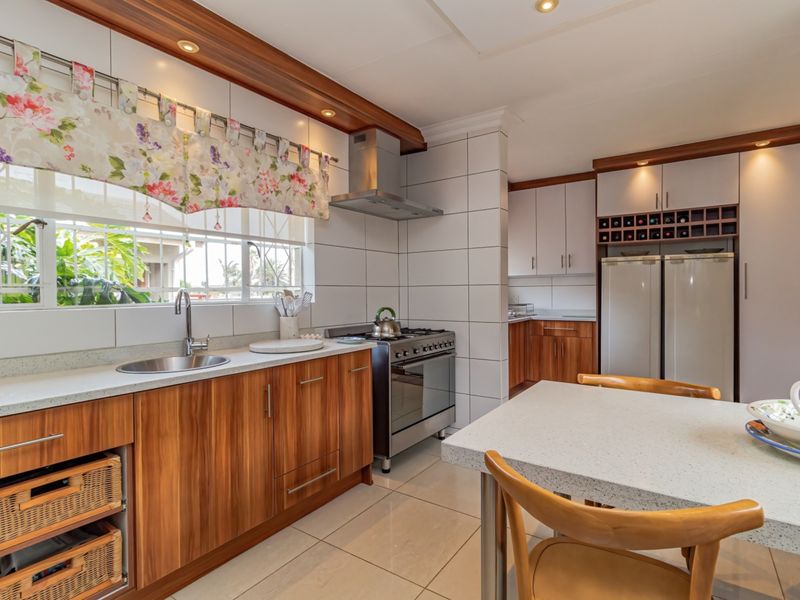 A well-maintained kitchen featuring wood-finish cabinetry, stone-look countertops, a gas stove with extractor, and integrated wine storage, offering a functional and warm cooking space.