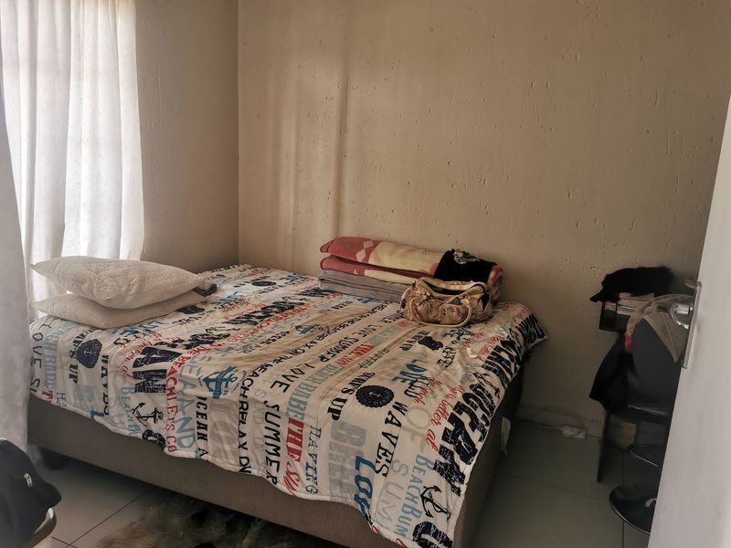 A compact bedroom featuring tiled flooring and a window with curtain rails, requiring minor wall repairs and cosmetic updates.