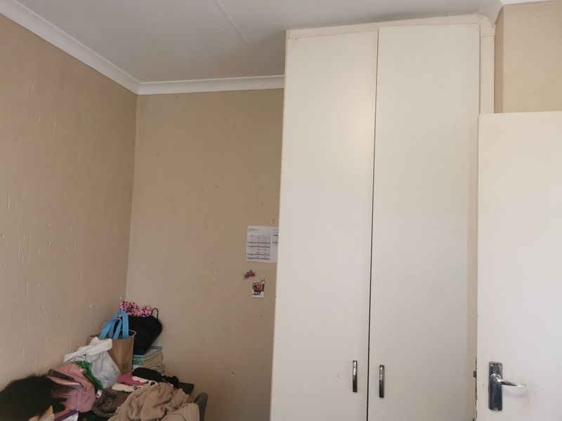 A bedroom featuring a built-in wardrobe and coving, requiring cosmetic updates to the wall finishes.
