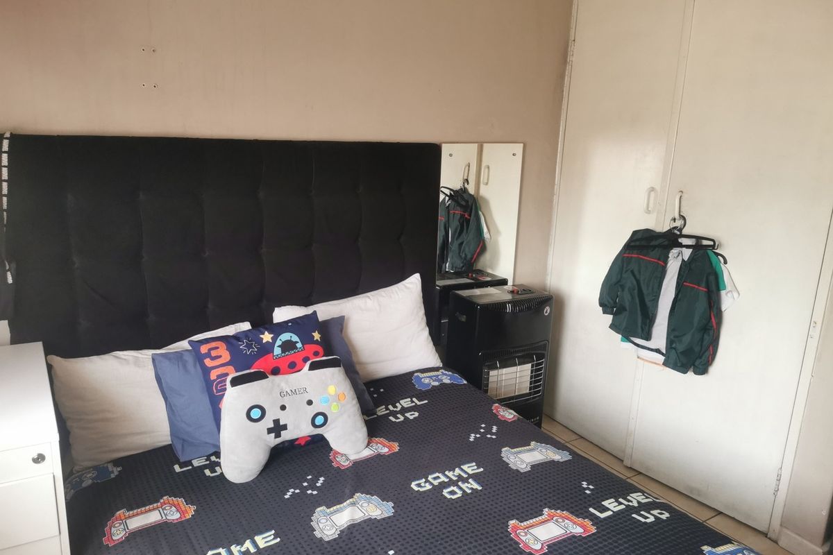 A bedroom featuring tiled flooring and a built-in wardrobe, requiring minor cosmetic updates to the wall finishes.