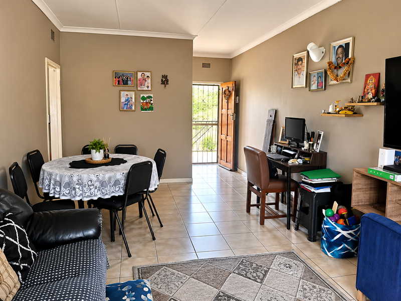 Open-plan living and dining area featuring neutral wall tones, tiled flooring, and direct access to an exterior security door.