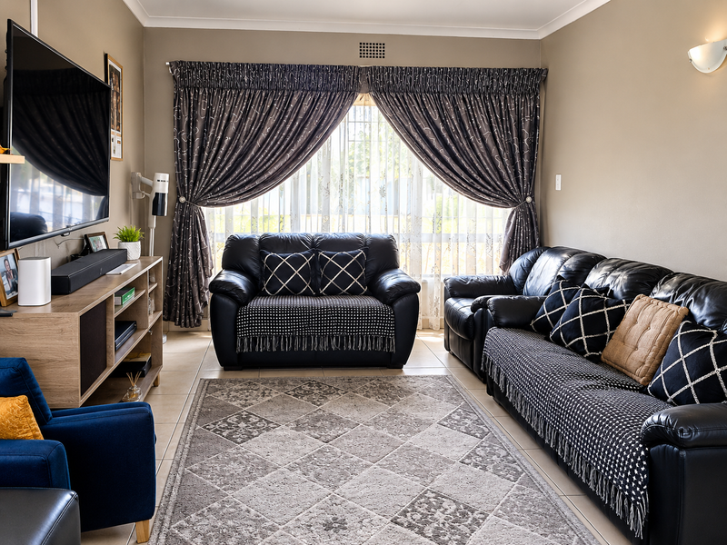 A well-maintained living room featuring tiled flooring, neutral wall tones, and large window treatments, providing a comfortable and functional space.