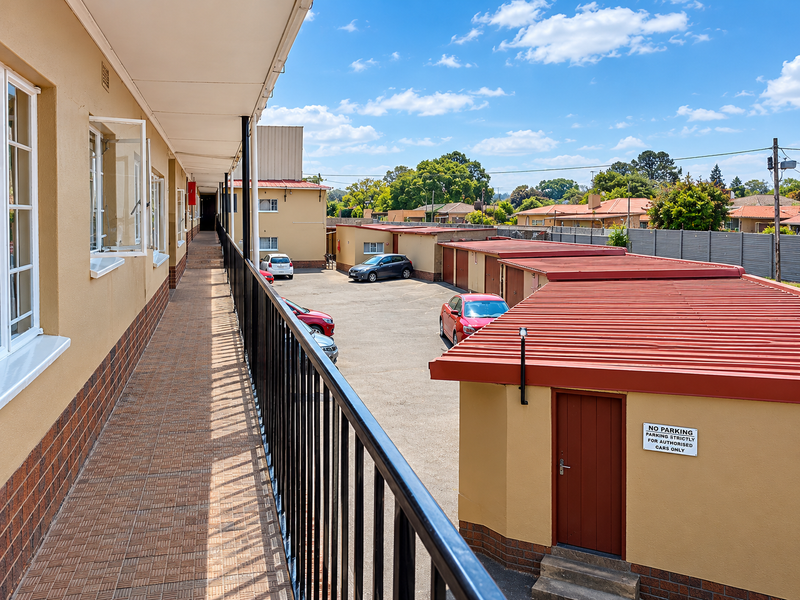 An elevated exterior walkway balcony overlooking the apartment complex parking area and garage structures.