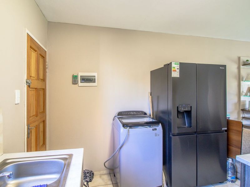 Open plan living area featuring a functional sink area, tiled flooring, and direct access to an exterior door.