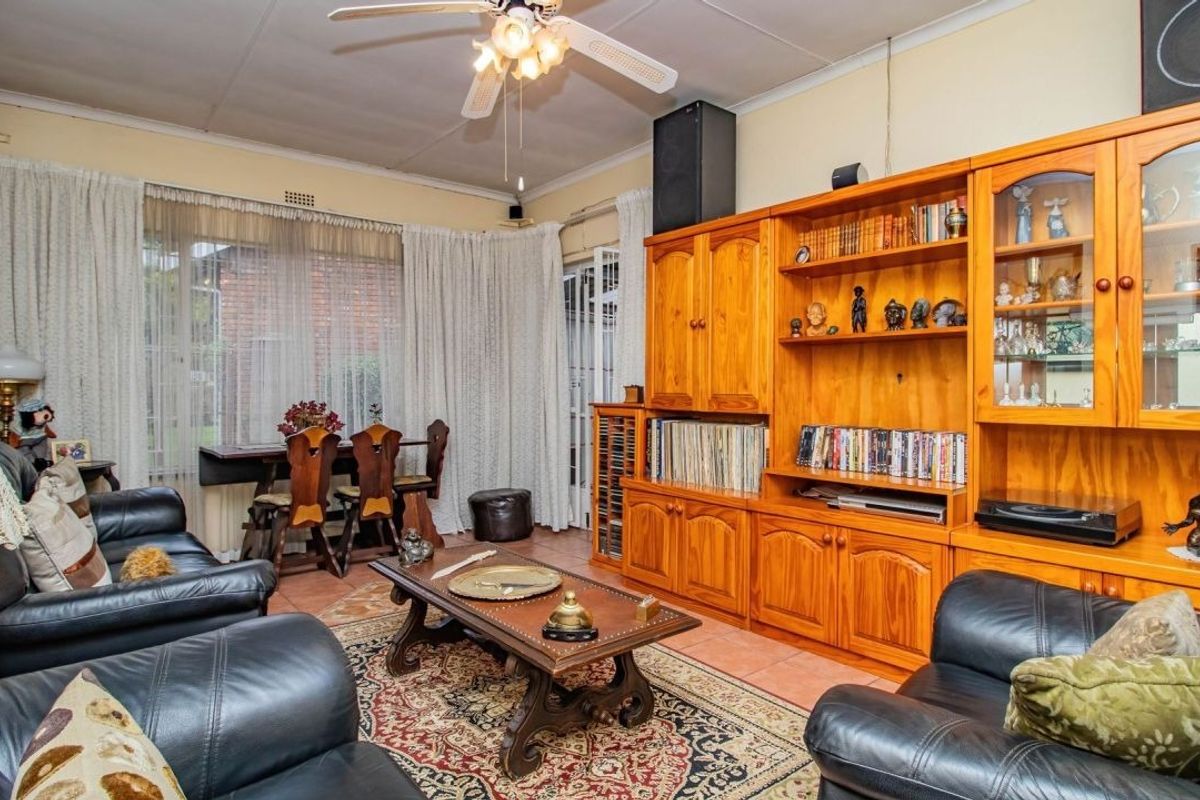 A spacious living room featuring tiled flooring, a ceiling fan, and large sliding glass doors providing access to the exterior.