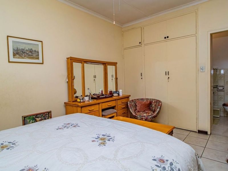 A bedroom featuring built-in cupboards, tiled flooring, and an adjoining en-suite bathroom.
