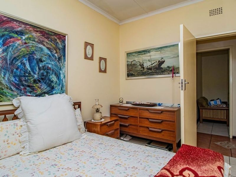 A standard bedroom featuring neutral wall tones, a doorway leading to an adjacent space, and integrated ventilation.