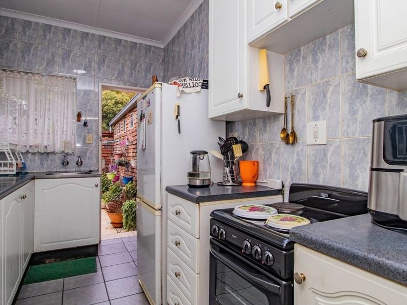 A functional kitchen featuring laminate countertops, built-in cabinetry, a freestanding stove, and tiled backsplash, with direct access to an outdoor area.