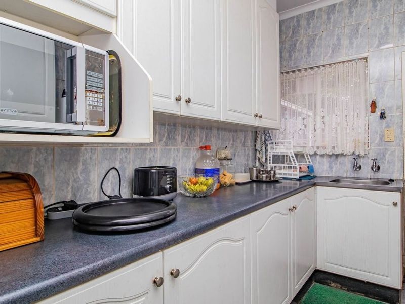 A functional kitchen featuring white cabinetry, laminate countertops, and a built-in microwave, with direct access to an outdoor area.