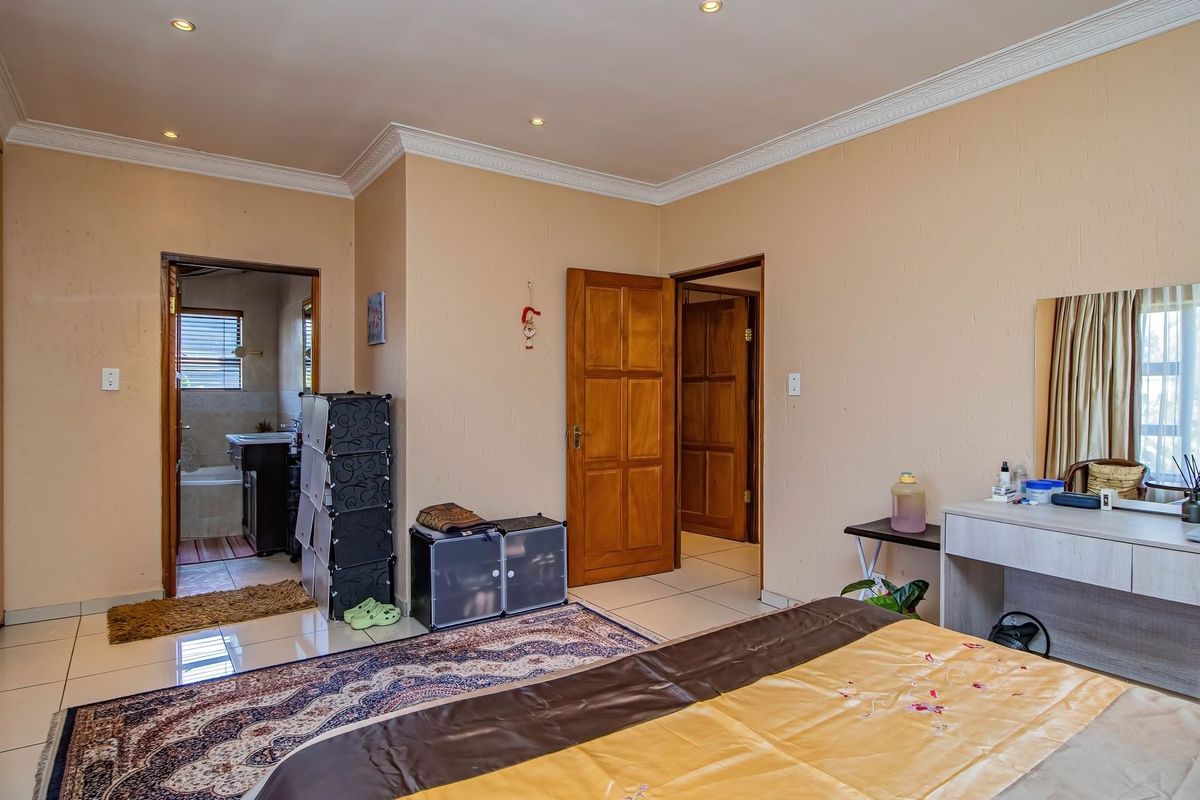 Spacious bedroom featuring tiled flooring, built-in cupboards, and direct access to an en-suite bathroom.