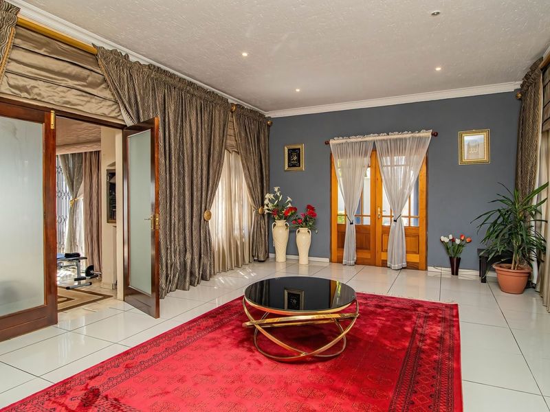 Spacious living room featuring tiled flooring, recessed downlighting, coved cornicing, and double wooden doors leading to adjacent areas.