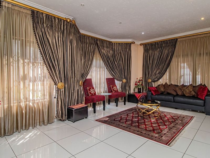 Spacious living room featuring large windows with floor-to-ceiling curtains and polished tiled flooring, offering a bright and comfortable atmosphere.