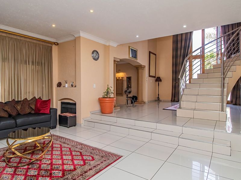 Spacious living area featuring polished tile flooring, a built-in fireplace, and an elegant staircase with a modern stainless steel balustrade.