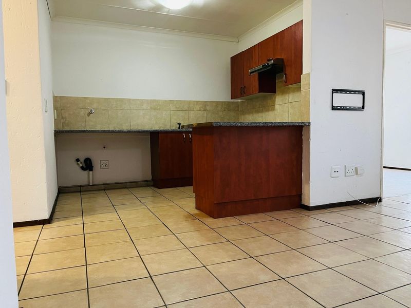 An empty kitchen featuring dark wood-look cabinetry, granite countertops, tiled flooring, and a tiled backsplash, ready for new appliances and personal touches.