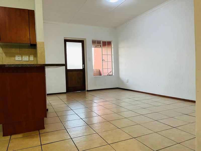 An open-plan living and kitchen area featuring tiled flooring, built-in cabinetry with granite countertops, and direct access to an outdoor space.