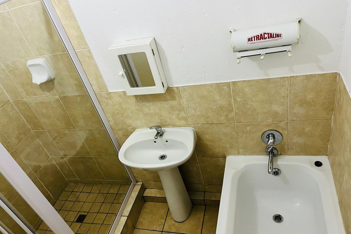 A functional bathroom featuring a pedestal basin, a separate shower enclosure, and a bathtub with tiled finishes throughout.