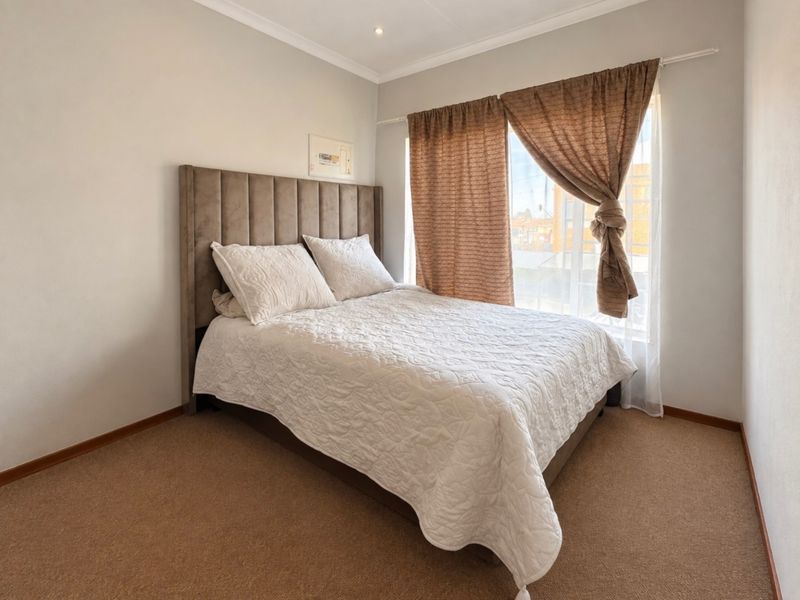 A well-maintained bedroom featuring neutral wall finishes, carpeted flooring, and recessed downlighting, providing a comfortable and functional living space.