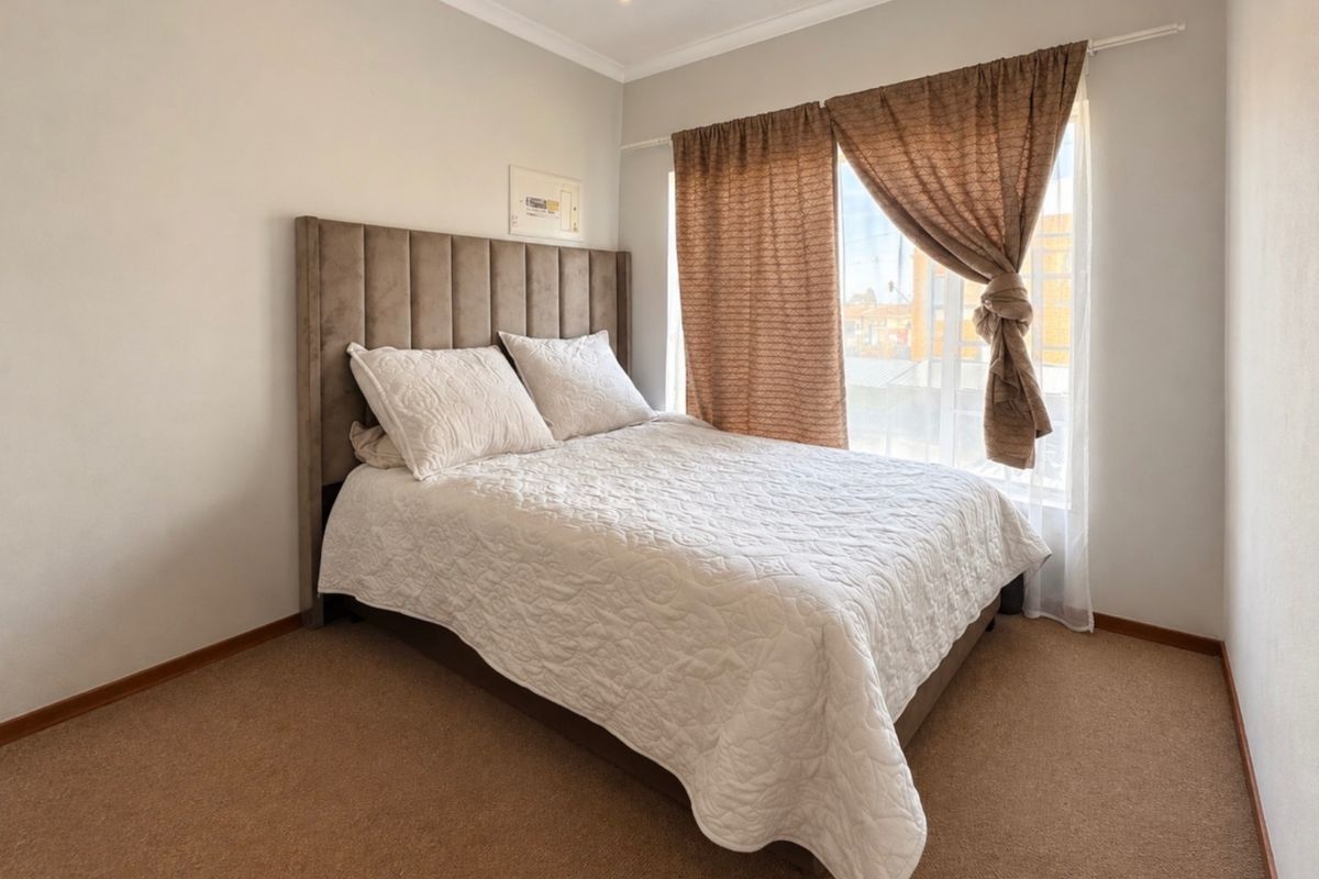 A well-maintained bedroom featuring neutral wall finishes, carpeted flooring, and recessed downlighting, providing a comfortable and functional living space.