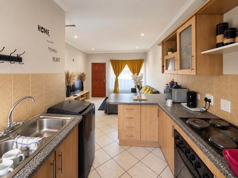 Open-plan kitchen and living area featuring light wood cabinetry, granite countertops, built-in oven, and tiled flooring throughout.