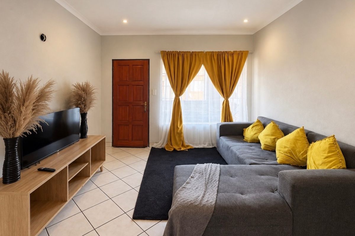 A well-maintained living room featuring neutral tiled flooring, recessed ceiling lighting, and a solid timber entrance door.