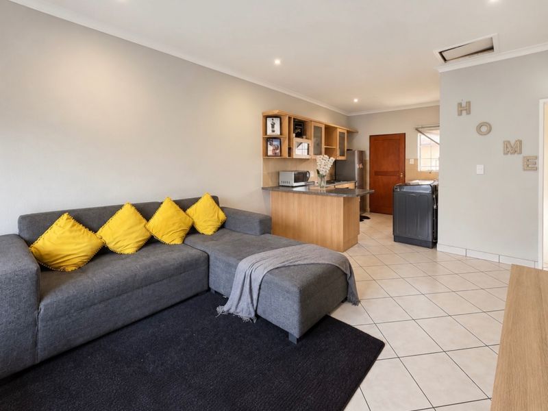 Open-plan living area featuring tiled flooring, recessed lighting, and a compact kitchen with built-in cabinetry and granite countertops.