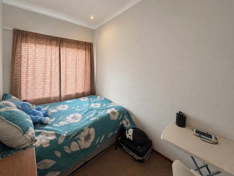 A compact bedroom featuring neutral wall finishes, recessed downlighting, and a window fitted with a curtain rod.