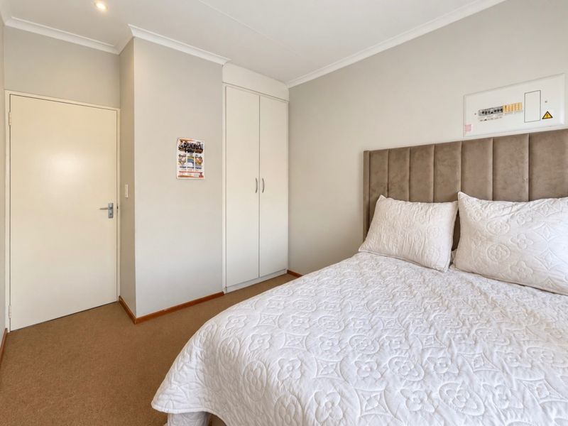 A well-maintained bedroom featuring neutral walls, carpet flooring, built-in wardrobe storage, and recessed ceiling lighting.