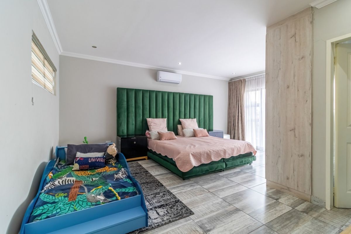 Spacious bedroom featuring tiled flooring, built-in cupboards, air conditioning, and a sliding door providing access to natural light.