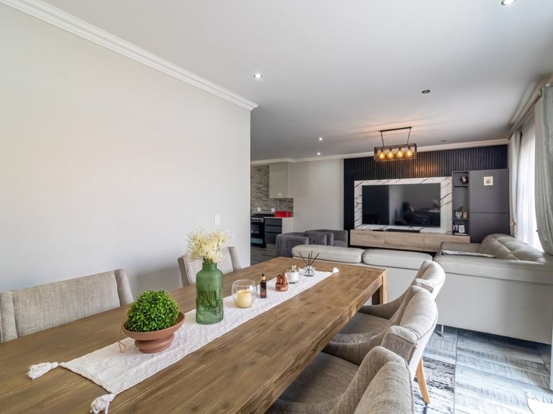 Spacious open-plan living and dining area featuring modern tiled floors, recessed lighting, and a stylish slatted feature wall with integrated media cabinetry.
