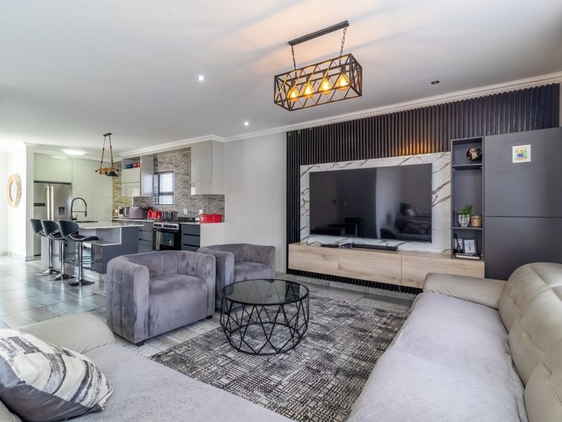Modern open-plan living area featuring a sleek kitchen with stone countertops and a stylish lounge with a slatted wood feature wall.