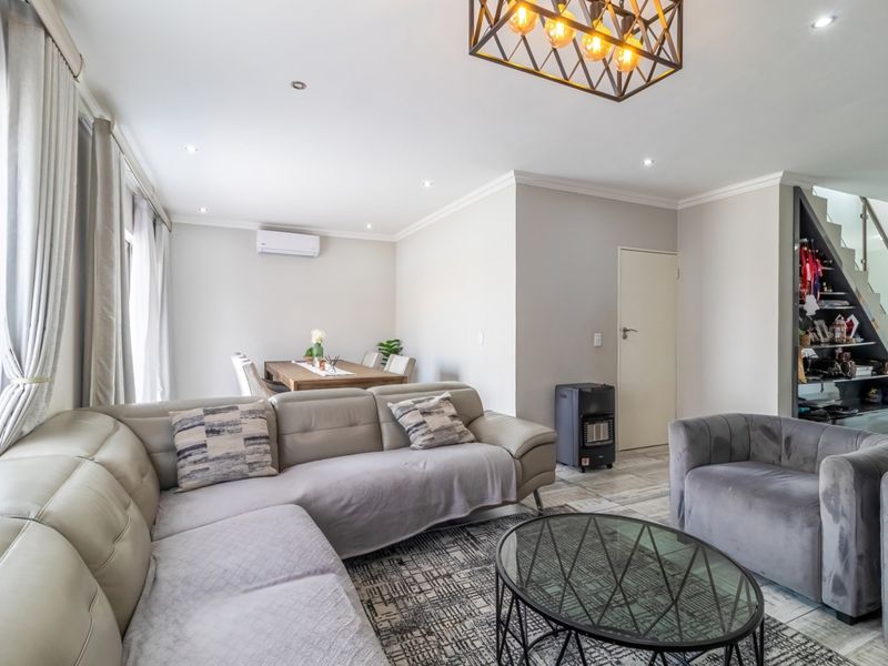 Spacious open-plan living and dining area featuring tiled floors, recessed lighting, and a modern staircase with a glass balustrade.