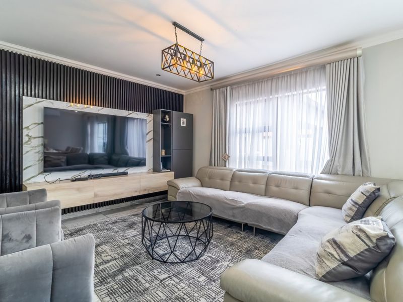 A modern living room featuring a striking slatted timber feature wall, marble-look media unit, and elegant pendant lighting, creating a sophisticated and comfortable space.