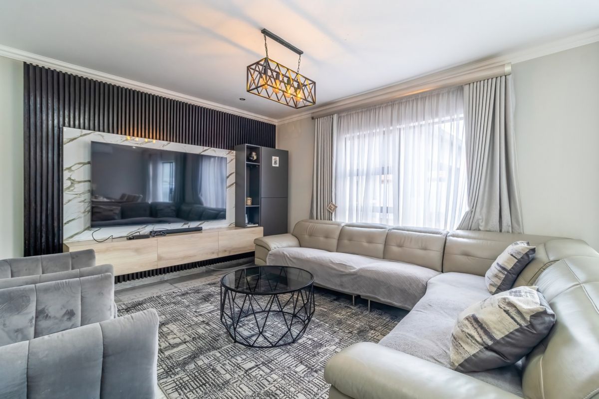 A modern living room featuring a striking slatted timber feature wall, marble-look media unit, and elegant pendant lighting, creating a sophisticated and comfortable space.