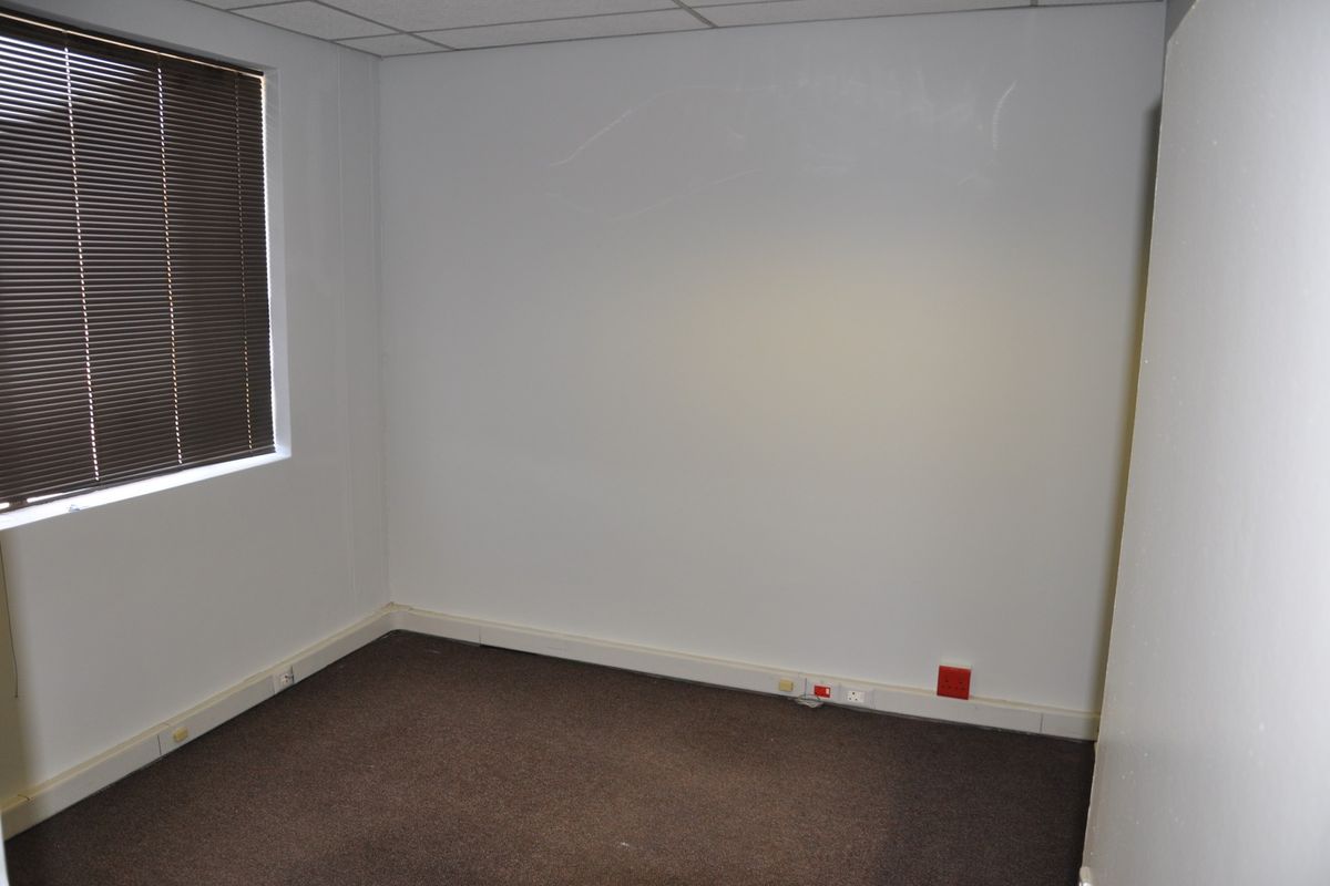 A vacant office space featuring carpeted flooring, a suspended ceiling, and integrated wall trunking for electrical connectivity.