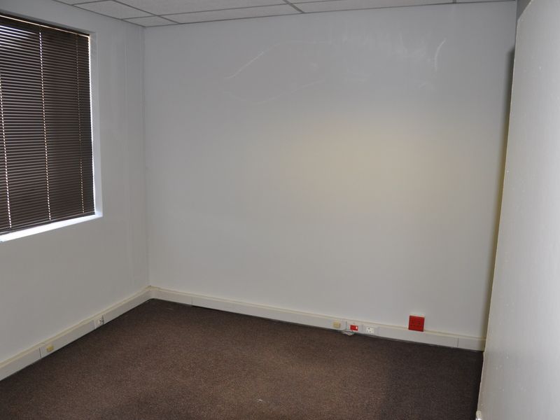 A vacant office space featuring carpeted flooring, a suspended ceiling, and integrated wall trunking for electrical connectivity.