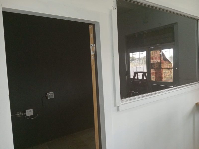 An empty office space featuring a dark accent wall, electrical outlets, and an internal glass partition window.