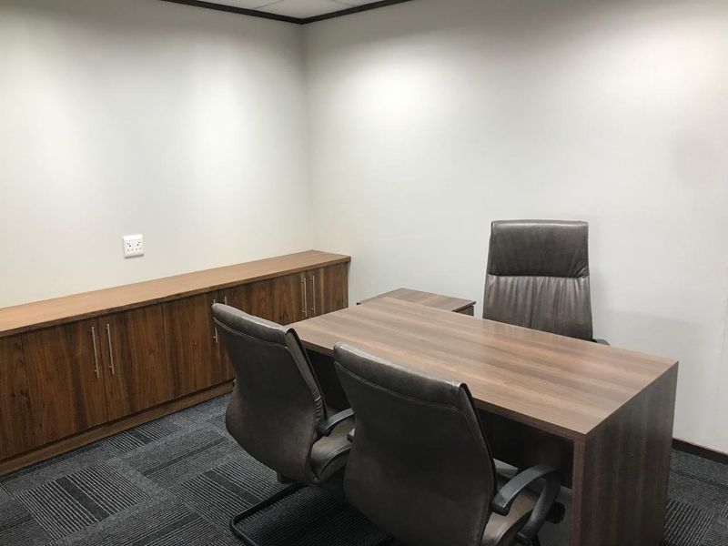 A professional office space featuring built-in wooden cabinetry, dark carpet flooring, and a drop ceiling, providing a clean and functional work environment.