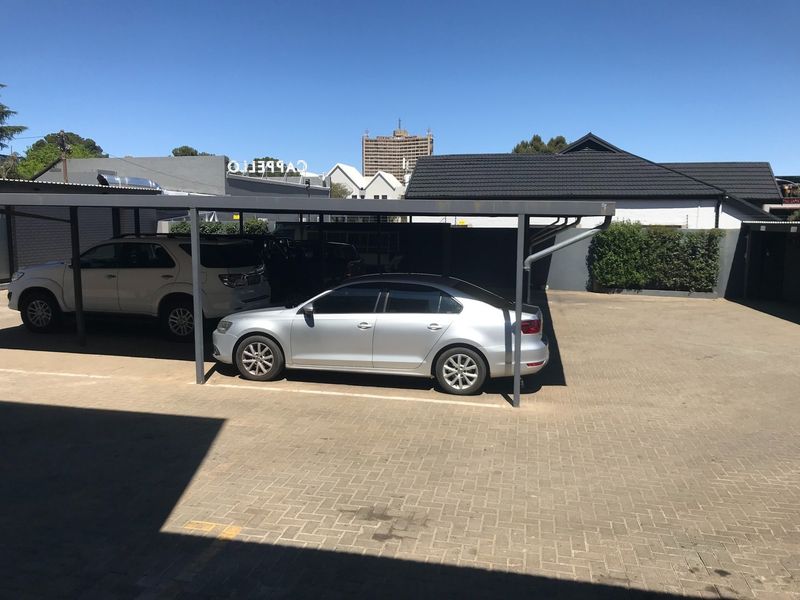 A paved outdoor parking area featuring a covered carport structure for vehicle protection.