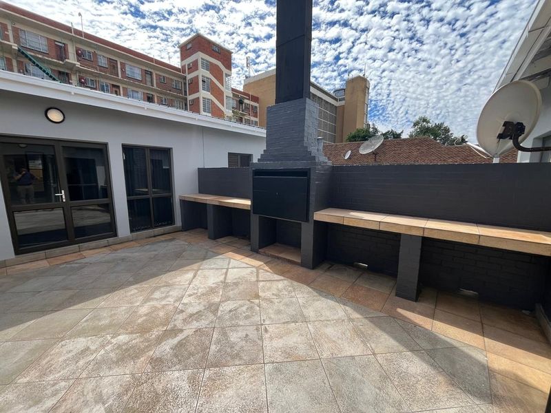 A well-maintained outdoor patio area featuring a built-in braai, tiled surfaces, and direct access to the office interior via sliding glass doors.