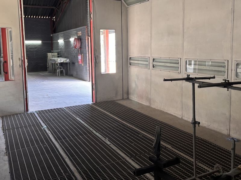 Industrial spray booth facility featuring metal floor grating, integrated lighting, and durable wall panels, suitable for automotive or industrial finishing applications.
